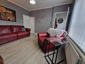 a living room with a red couch and a table at Pet-Friendly Home with Secure Garden nr Beamish in Birtley +16 photos