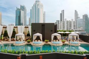a swimming pool with umbrellas and a city skyline at Canopy By Hilton Bangkok Sukhumvit in Bangkok