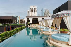 a pool with chairs and umbrellas on top of a building at Canopy By Hilton Bangkok Sukhumvit in Bangkok