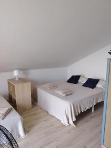 a white bedroom with two beds with blue pillows at La Petite in Cogoleto