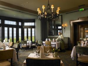 a woman standing in a dining room with tables at Trump International Golf Links & Hotel Doonbeg Ireland in Doonbeg