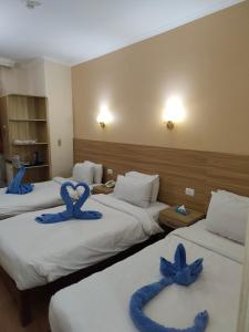 a hotel room with three beds with blue bows on them at S S Luxor Hotel in Luxor