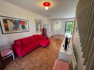 a living room with a red couch and a table at Villa Dosso Fiorito in Lignano Sabbiadoro