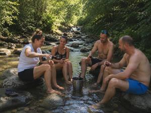 a group of people sitting on rocks in a river at Bellevue Beam House in Covasna