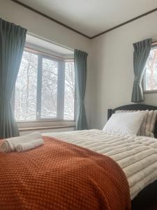 a bedroom with a large bed and a window at Corduroy Ski Lodge Madarao Tangram in Shinano