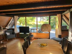 a living room with a table and chairs and a television at Authentic wooden summer house in Øster Hurup