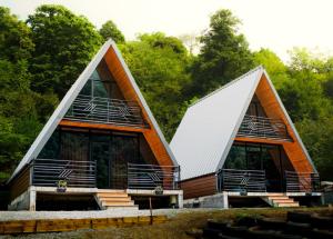a house with two triangular roofs with trees in the background at Machakhela Peaks in Sindietʼi