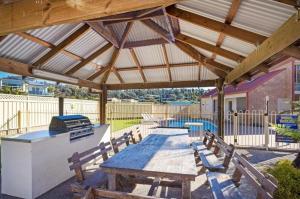 a wooden pavilion with a picnic table and a grill at Edna's Retreat in Tathra