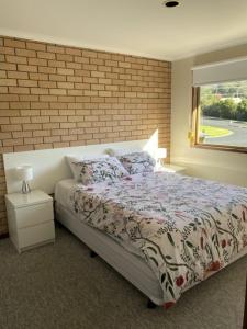 a bedroom with a bed and a brick wall at Edna's Retreat in Tathra