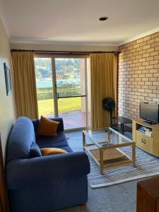 a living room with a blue couch and a glass table at Edna's Retreat in Tathra