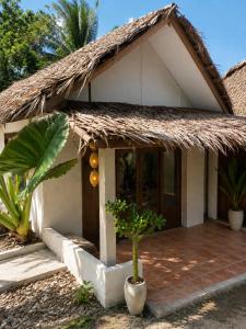 a small house with a thatched roof and a plant at Nomad Beach House, Koh Lanta in Ko Lanta