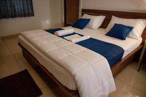 a large bed with blue and white sheets and pillows at Sushi Greens Suites in Dāvangere +2 photos