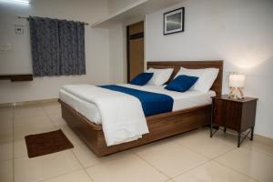a bedroom with a large bed with blue pillows at Sushi Greens Suites in Dāvangere