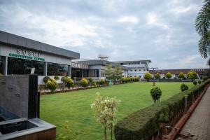 a building with a large lawn in front of it at Sushi Greens Suites in Dāvangere
