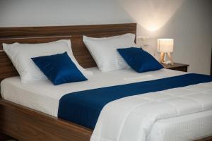a bedroom with a large bed with blue and white pillows at Sushi Greens Suites in Dāvangere