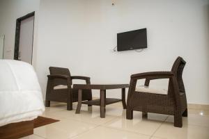 a room with chairs and a table and a tv at Sushi Greens Suites in Dāvangere