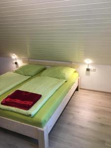 a bed with green sheets and a red blanket on it at Ferienwohnung am Bodensee in Kressbronn am Bodensee