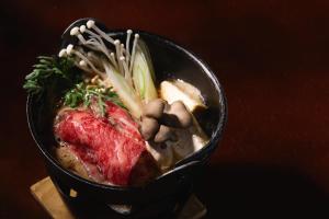 a black bowl of food with meat and vegetables at Nishihoppo Onsen HOTEL in Yamanouchi