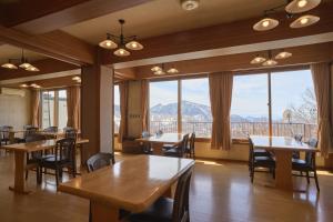 a restaurant with tables and chairs and large windows at Nishihoppo Onsen HOTEL in Yamanouchi +47 photos