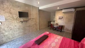 a bedroom with a pink bed with a tv on the wall at Bankrut Backpack in Sathani Ban Krut