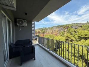 a balcony with a chair and a view of the forest at Shengjin Apartament 5 M in Shëngjin