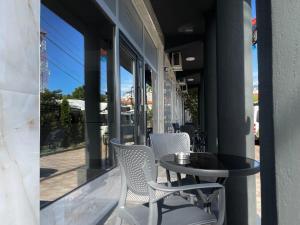 a patio with two chairs and a table and some windows at Hotel Heimli in Prishtinë