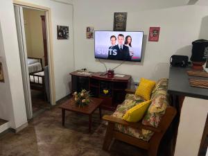 a living room with a couch and a flat screen tv at Casa no Centro, 3 Camas, Garagem, com Netflix e Amazon Prime in Rio das Flores
