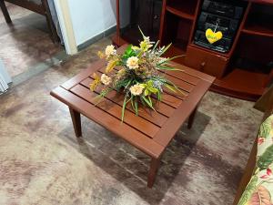 a wooden table with a bouquet of flowers on it at Casa no Centro, 3 Camas, Garagem, com Netflix e Amazon Prime in Rio das Flores +41 photos