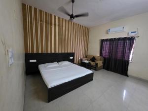 a bedroom with a bed and a chair in it at Hotel MNP in Jabalpur
