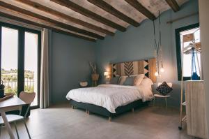 a bedroom with a large bed in a room with windows at Can Alemany in Santa Margarita de Mombúy
