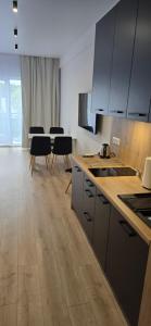 a kitchen with white cabinets and tables and black chairs at White Pearls Apartaments Dąbki in Dąbki