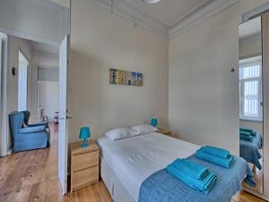 ein weißes Schlafzimmer mit einem Bett und einem blauen Stuhl in der Unterkunft Almirante Reis Apartment in Lissabon