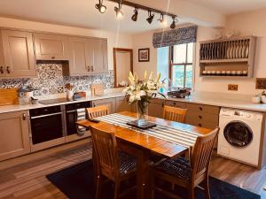 a kitchen with a wooden table with chairs and a vase of flowers at Heigh Farmhouse in Lancaster