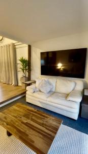 a living room with a white couch and a large screen at Overwater on the Murray in Murray Bridge