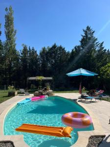 a swimming pool with two rafts and an umbrella at Atelier Provençal in La Celle-sous-Gouzon