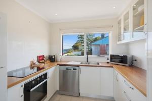 a kitchen with white cabinets and a window at Whale Stay in Tathra