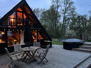 a patio with a table and chairs and a house at Authentic wooden summer house in Øster Hurup