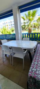 a white table and chairs on a balcony with a palm tree at kabila vista vuestra a la piscina Z6 in Martil