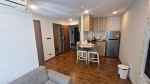 a kitchen and a living room with a table and a couch at Stasia Suites Sriracha in Ban Fang Daeng