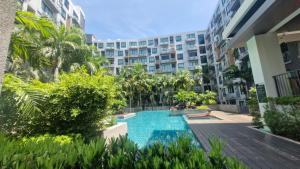 an apartment complex with a swimming pool in front of a building at Stasia Suites Sriracha in Ban Fang Daeng