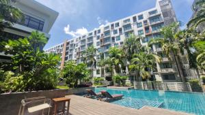 a hotel with a swimming pool in front of a building at Stasia Suites Sriracha in Ban Fang Daeng