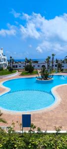 a large blue swimming pool with palm trees and buildings at kabila vista vuestra a la piscina Z6 in Martil