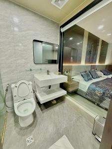 a bathroom with a toilet and a sink and a bed at Skyport Hotel in Manila
