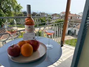 a plate of fruit and two glasses of wine on a table at Des Roses Hotel in Platanias