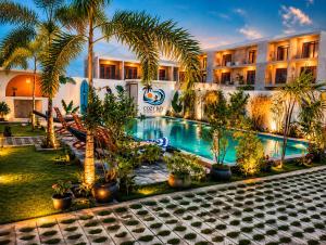 a hotel with a pool with palm trees and a building at Cozy Bay Hotel in Arugam Bay