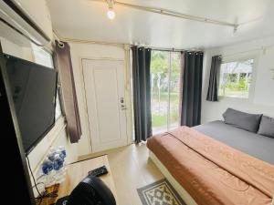 a bedroom with a bed and a flat screen tv at 3199 Cafe' Latya & Bed in Ban Lum Makok