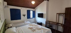 a bedroom with two beds and blue shuttered windows at Solar Itacaré - Charme e aconchego. in Itacaré