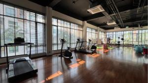 a gym with exercise equipment in a large room with windows at Stasia Suites Sriracha in Ban Fang Daeng