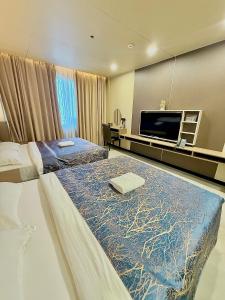 a hotel room with two beds and a flat screen tv at Skyport Hotel in Manila