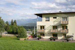 a house with a balcony and a green lawn at B&B Garni Schorneck in Brunico